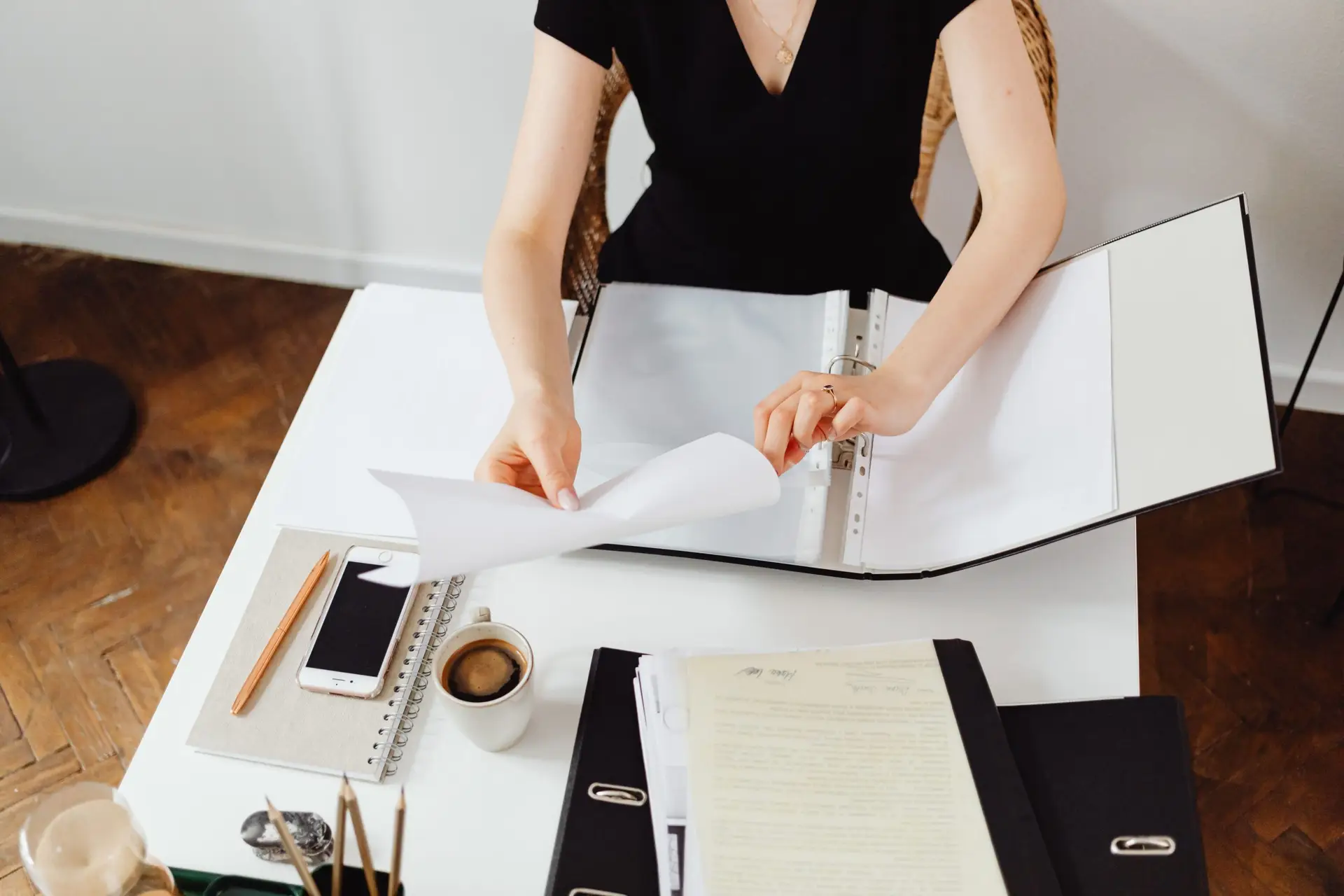 Femme à son bureau, rangeant des documents, illustrant un environnement de travail professionnel.